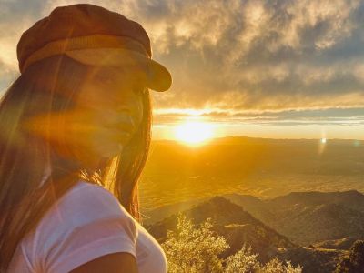 Cinthya Carmona is taking a selfie with sunset in the background.